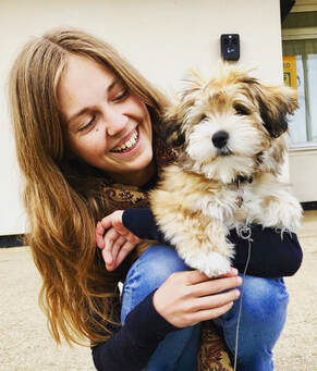 Photo of Beth holding her small, fluffy dog, Neville. 